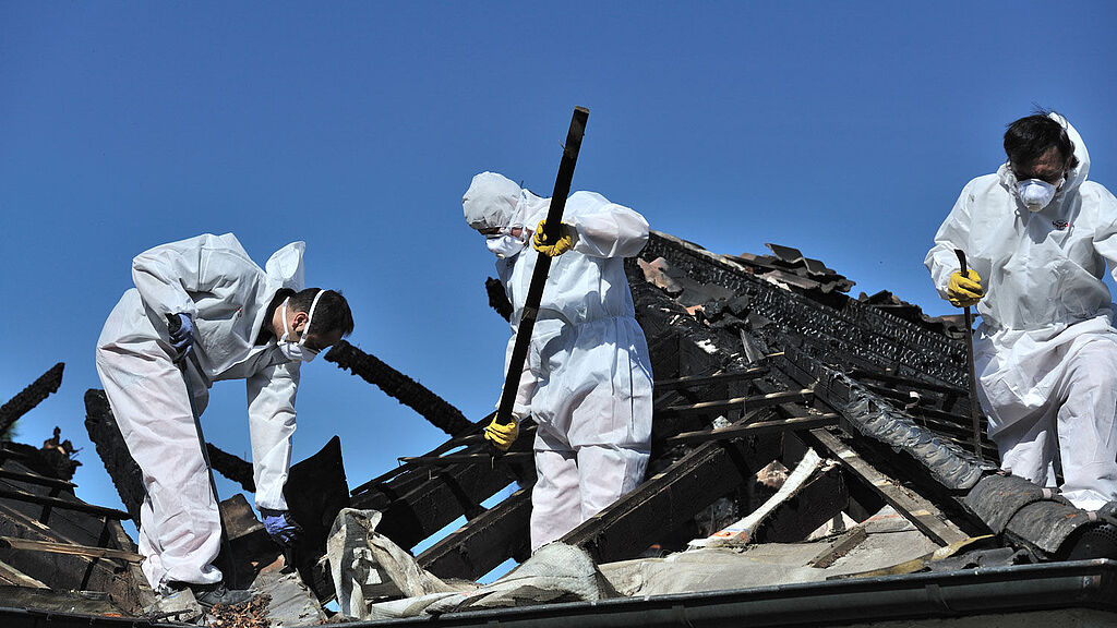 3 Männer auf dem Dach entfernen Material nach Brand